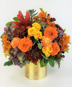 orange yellow and burfundy flowers in round tin