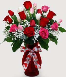 Let two lips meet this Valentine's after gifting this best-selling arrangement full roses and tulips! red, pink , white and all the classic colors of Valentine's Day mix in a red glass vase with a Cute Bow. Approximate size of Standard is 10"W x 15"H.
