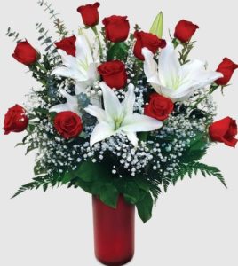 A dozen roses are complimented by the beauty and sweet scent of fragrant white lilies.