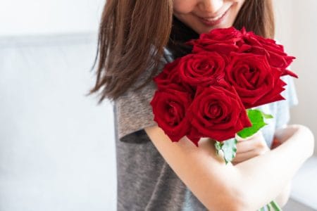 Woman smiling at her bouquet of red roses